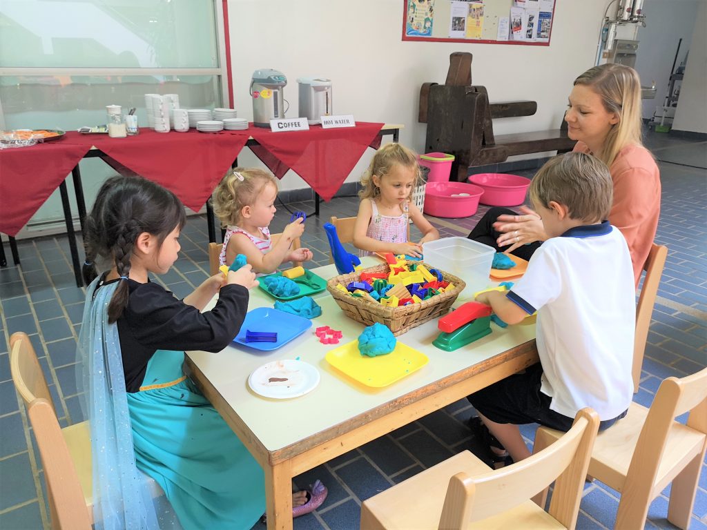 Teacher plays with children on a play table