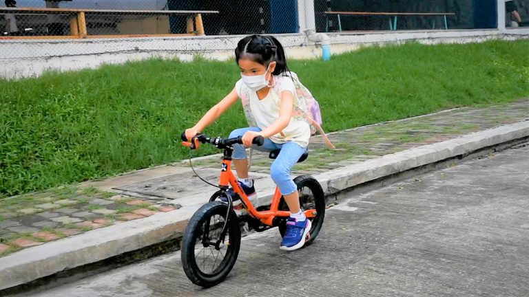 Small girl rides on bicycle to school